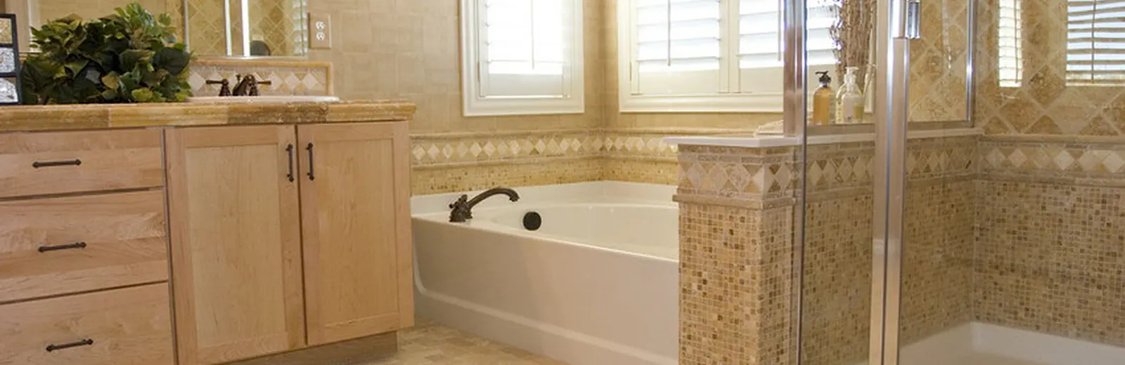 Bathroom with a drop-in tub, tile surround and plantation shutters