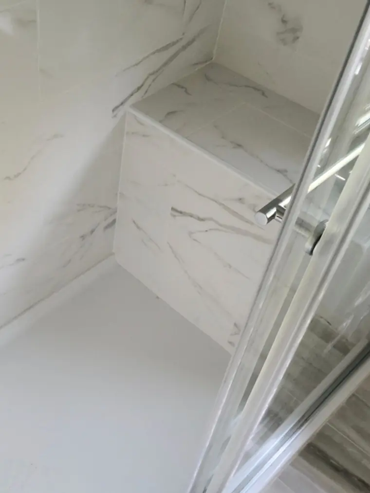 Marble-look tiled shower with a recessed niche