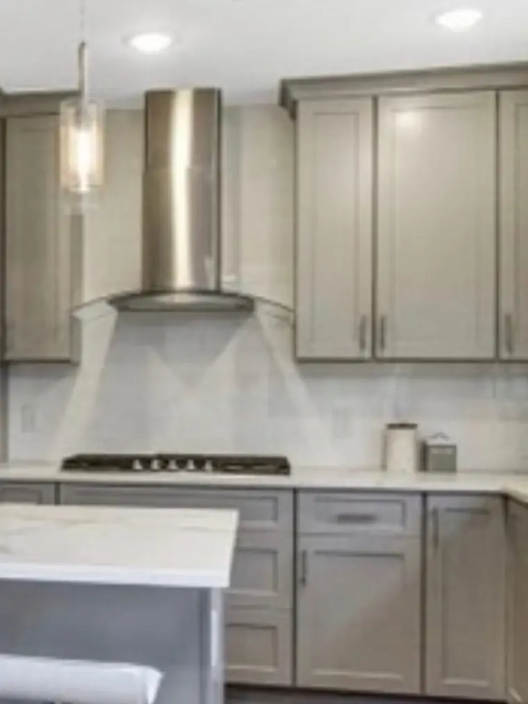 Gray kitchen with a stainless range hood and quartz counters