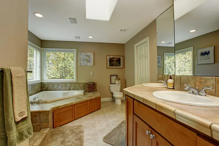 Bathroom with a corner soaking tub, oak vanity and skylight