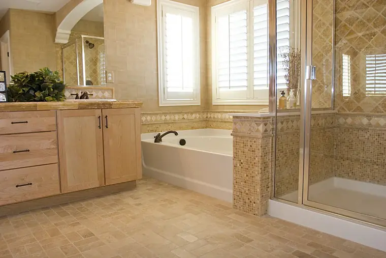 Bathroom with a drop-in tub, tile surround and plantation shutters
