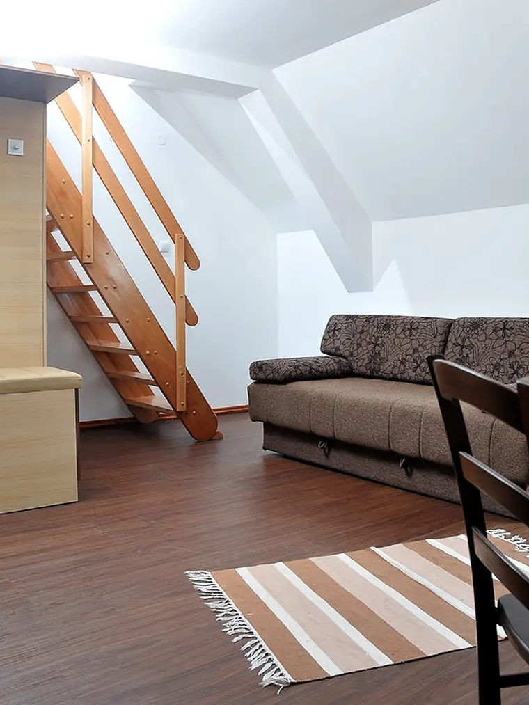 Attic conversion with exposed wood stairs, sofa and hardwood floor
