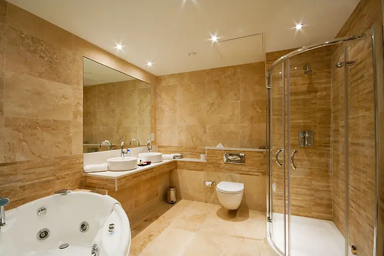 Travertine bathroom with a walk-in glass shower and vessel sink