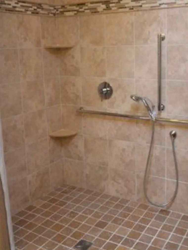 Tiled walk-in shower with a corner seat and grab bar