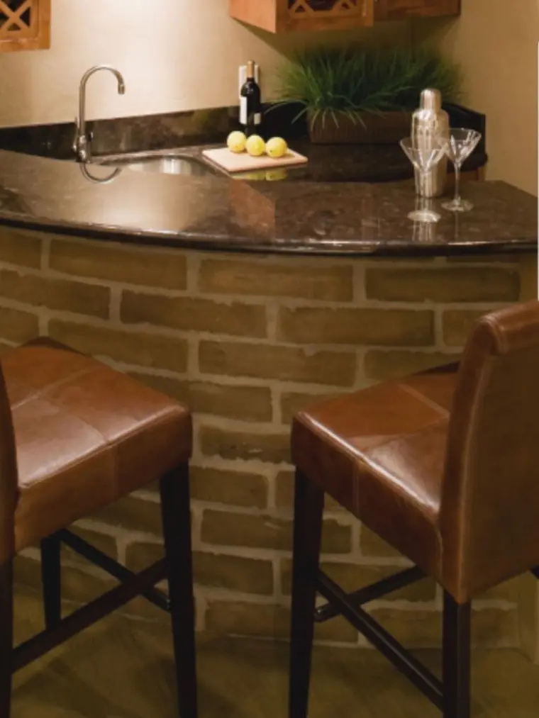 Basement bar with a brick front, granite top and leather stools