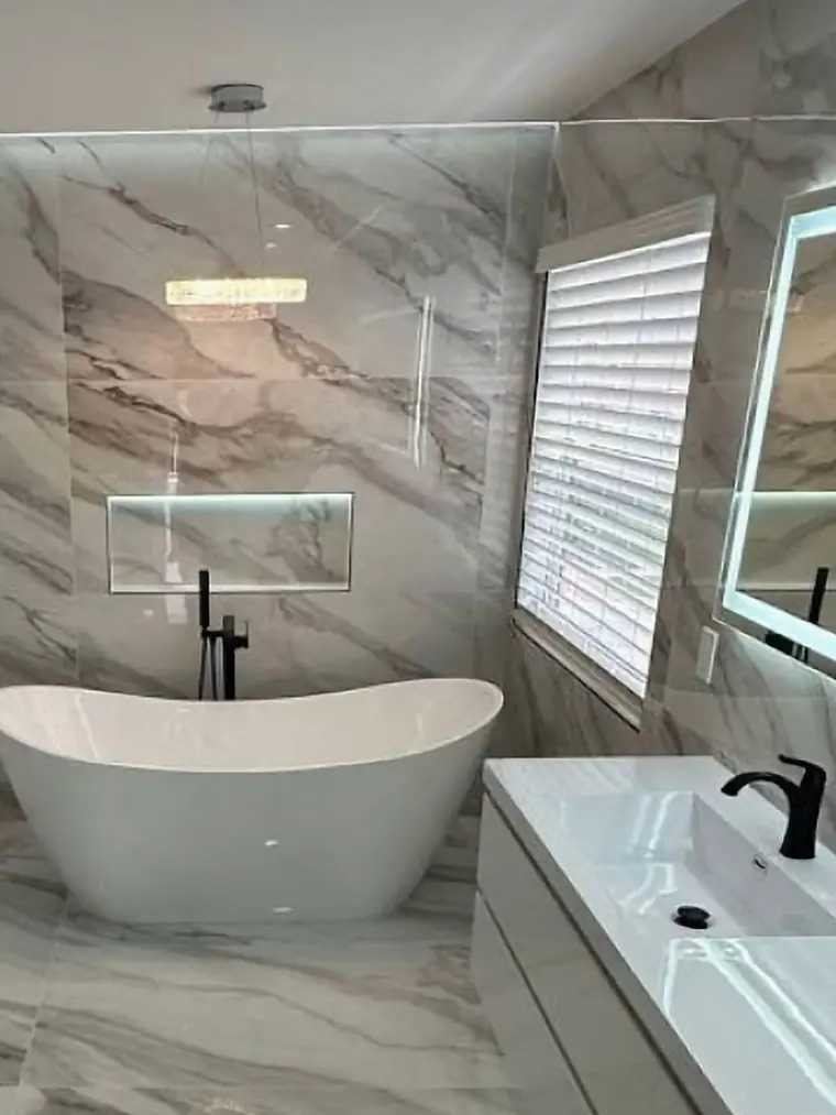 Bathroom with a freestanding tub, marble walls and black fixtures
