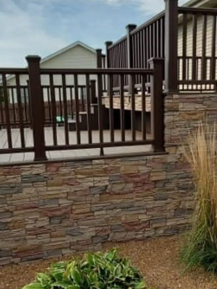 Composite deck on a stacked stone base with dark railings
