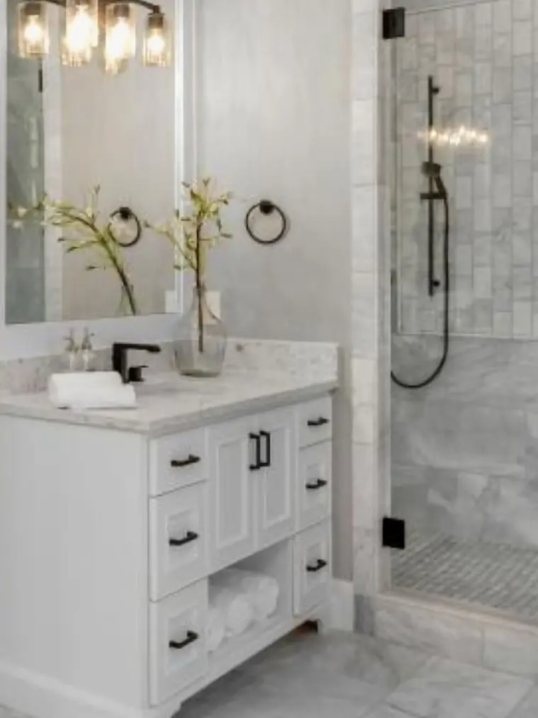 White bathroom vanity with a marble top and black pulls