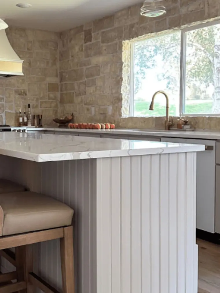 Kitchen island with a stone accent wall and beadboard panels