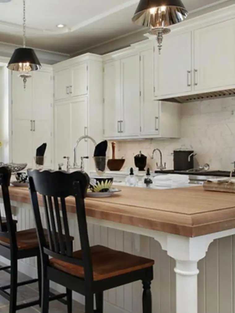 White kitchen with butcher block island and black chairs