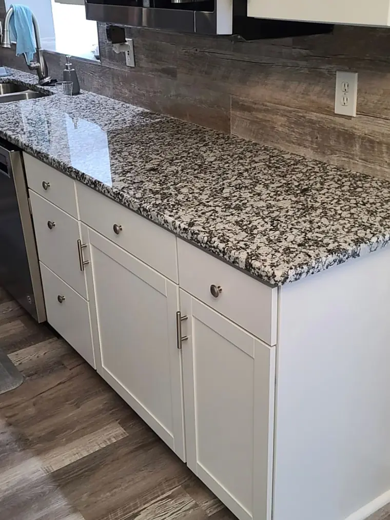 White kitchen cabinets with speckled granite counters