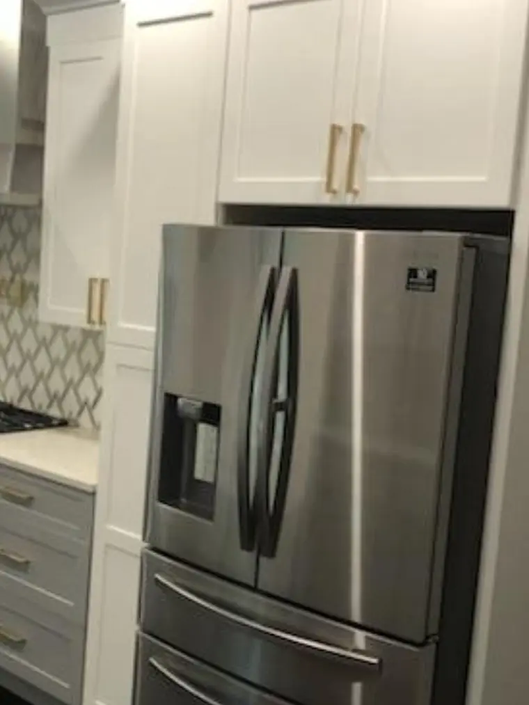 Kitchen remodel with white cabinets, gold pulls and a stainless refrigerator