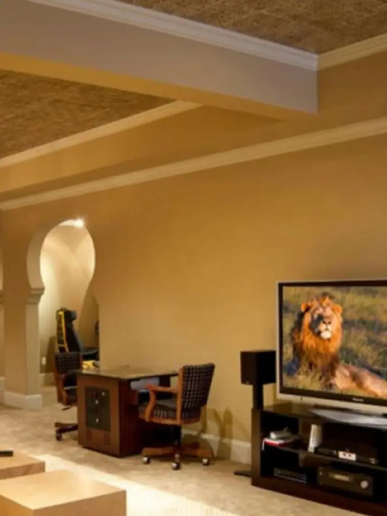 Finished basement with arched openings, a wet bar and a wall-mounted TV
