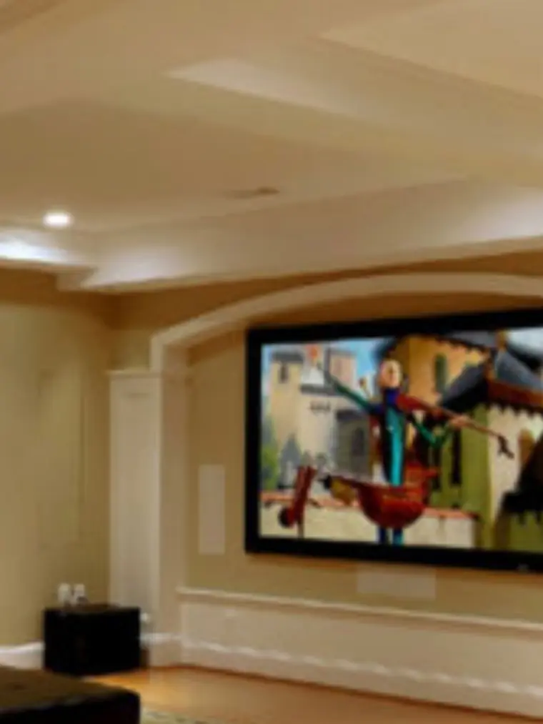 Basement home theater with a stone feature wall and tray ceiling
