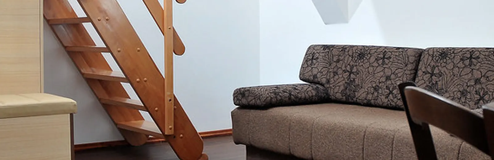 Attic conversion with sloped ceiling, wood stairs and a sofa