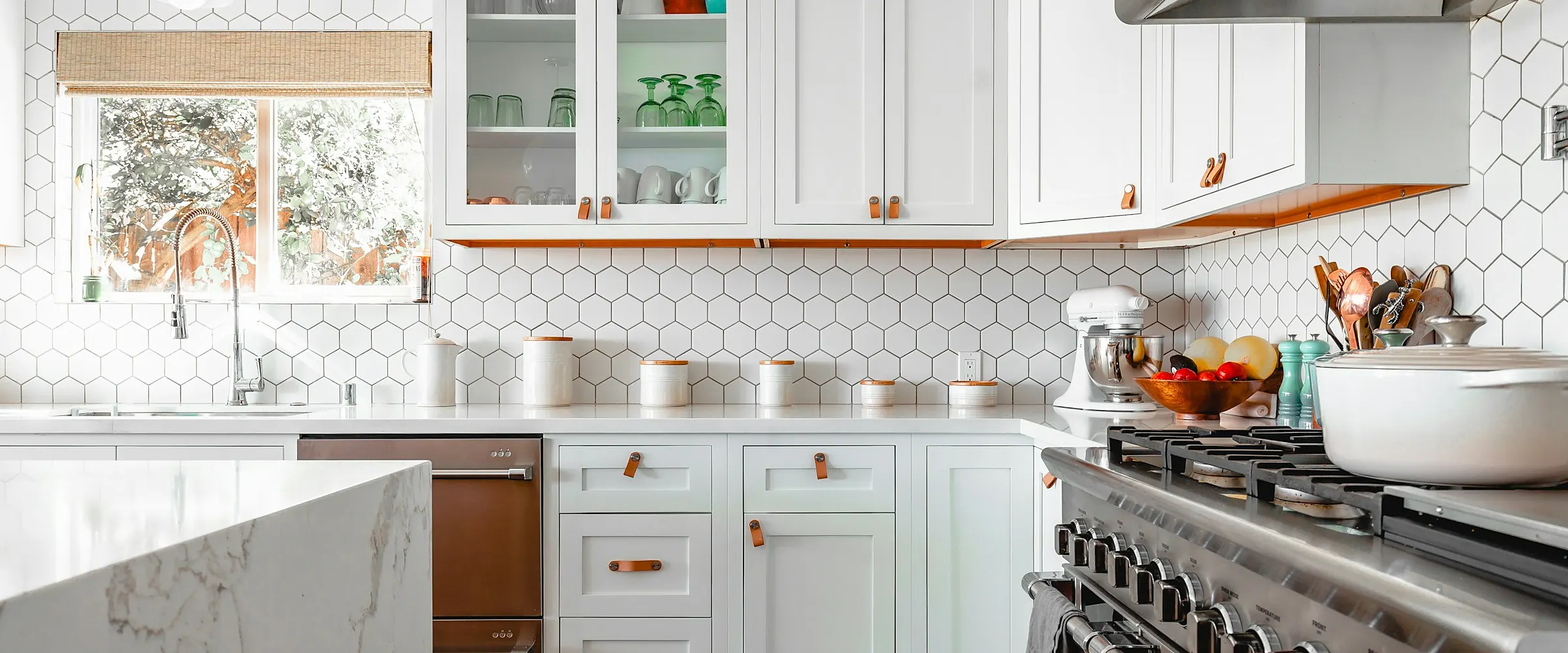 Remodeled white kitchen with a professional range and marble counters